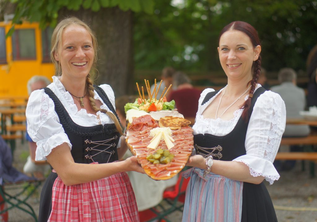 Zwei Mitarbeiterinnen mit einer Brotzeit auf einem Holzbrett