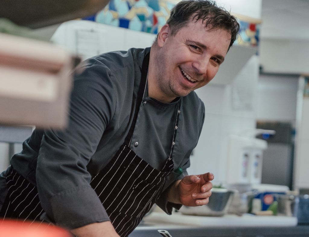 Koch hinter Tresen richtet Speisen an