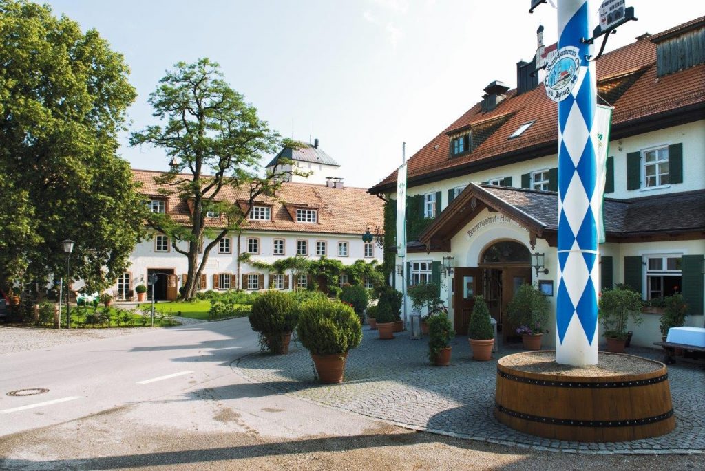 Außenansicht des Brauereigasthof Hotel Aying mit Maibaum