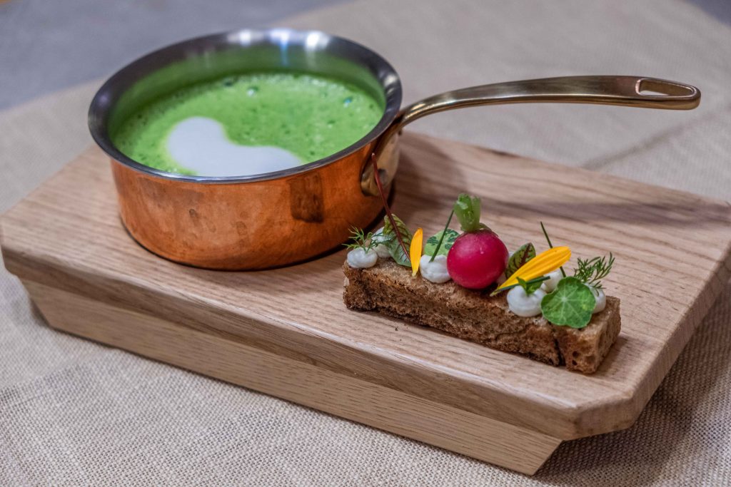 Holzbrett mit Pfännchen mit Kräutersuppe