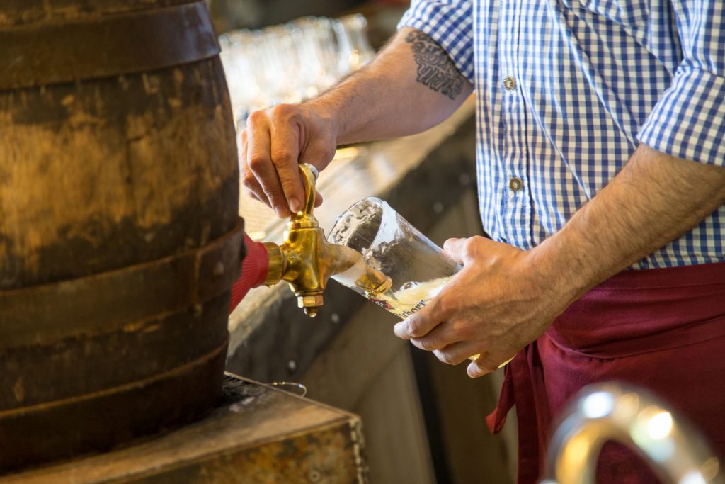 Ein Bier wird aus dem Holzfass gezapft