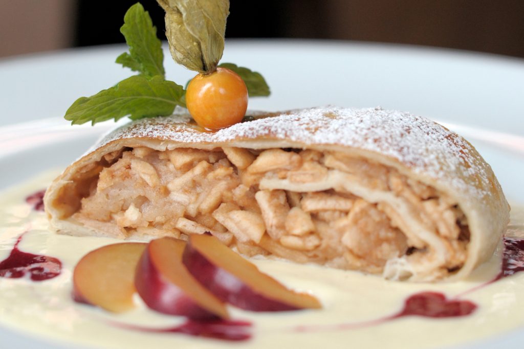 Ein Teller Apfelstrudel mit Vanillesauce und frischen Früchten