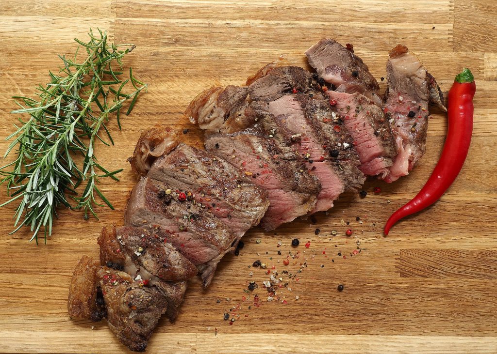 Brett mit aufgeschnittenem Fleisch und Chili