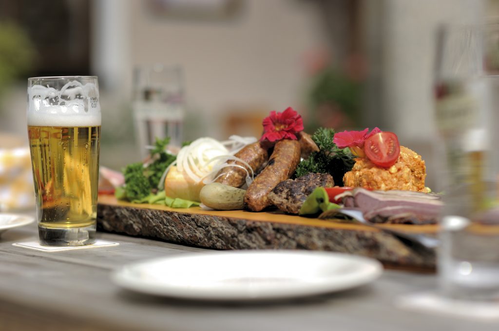 Brotzeitbrettl mit verschiedenen Spezialitäten und einem frisch gezapften Bier