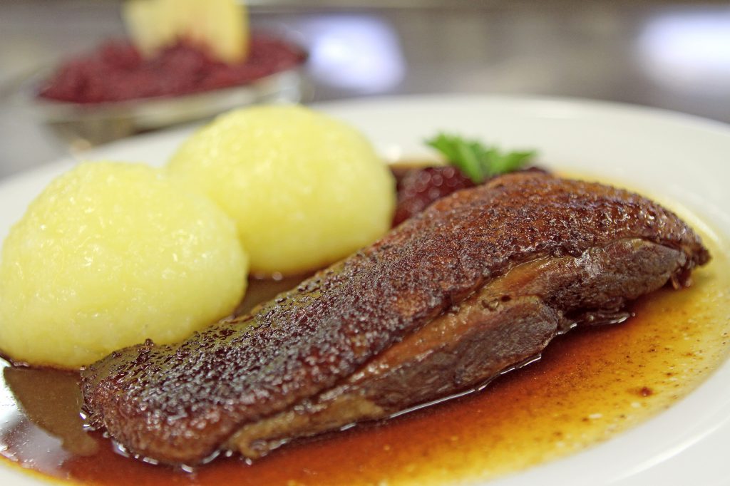 Ein Teller mit einem Stück Gänsebrust und Kartoffelknödel