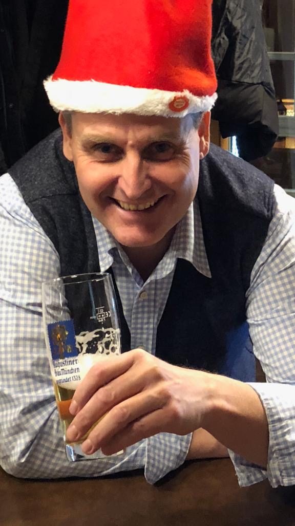 Mann trinkt einen Bier mit Nikolausmütze auf