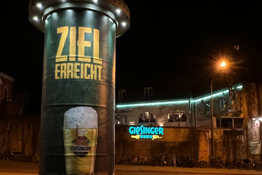 Giesinger Bräu nachts Haupteingang mit Litfaßsäule "Ziel erreicht"