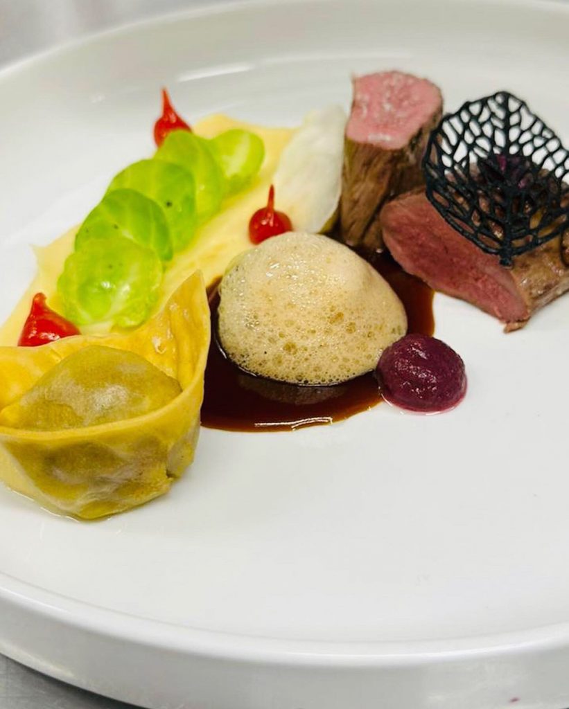 weißer Teller mit angeschnittenem Filet mit Ravioli und Püree