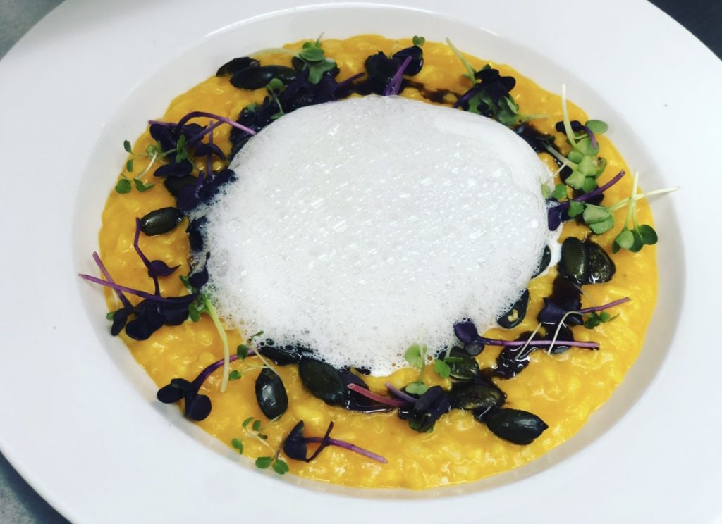 Suppenteller mit Kürbissuppe, sprossen, Kürbiskerne und Schaum