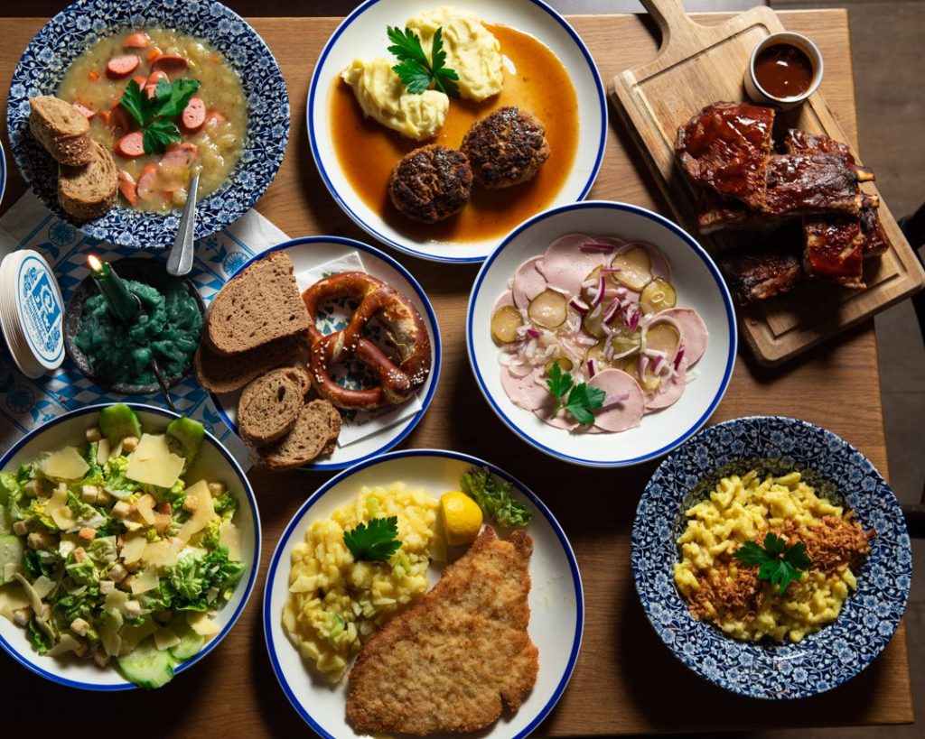 Tisch mit diversen Speisen, wie Fleischpflanzl, Schnitzel und Wurstsalat