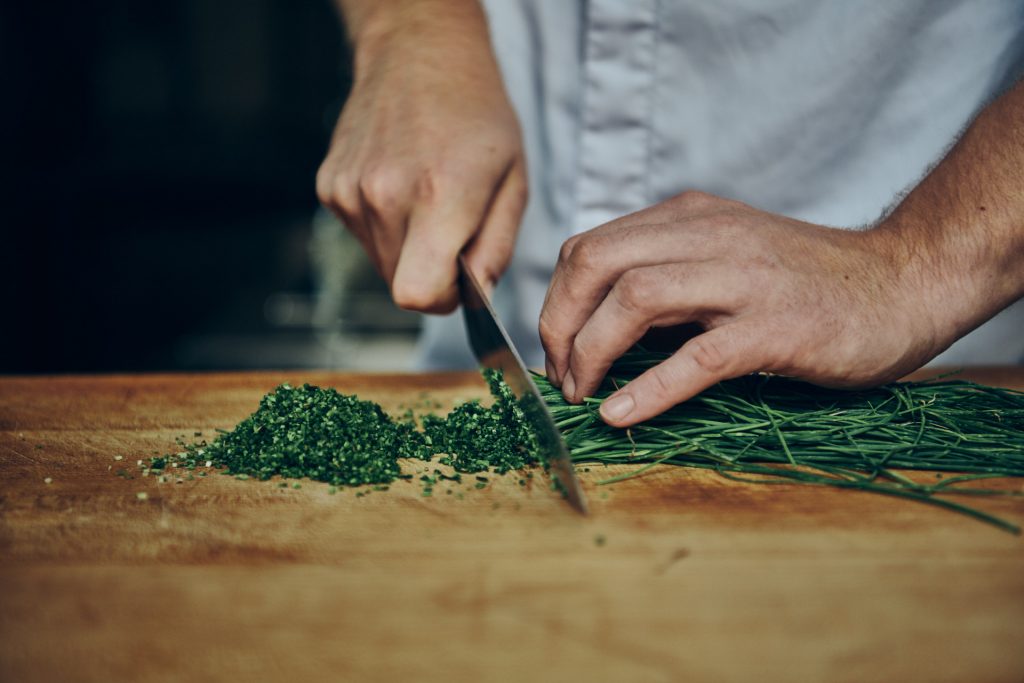 Steiner Wirt, Person schneidet Schnittlauch auf Holzoberfläche