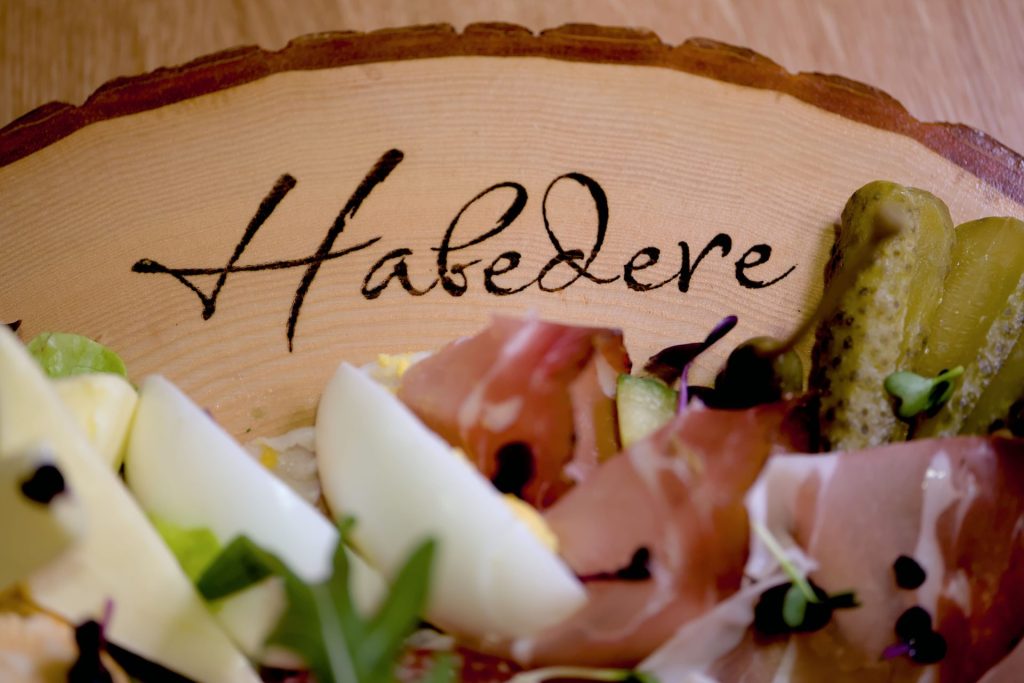 gebrandetes Brotzeitbrett mit Habedere und belegt mit Speck, Käse und Essiggurken