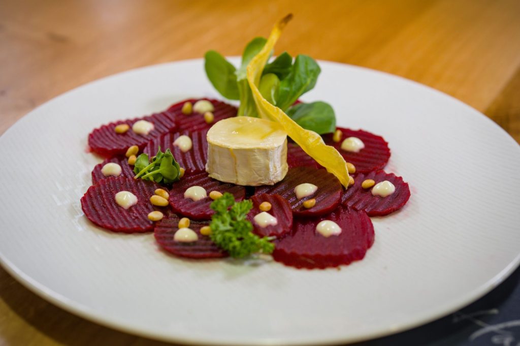 Rote Beete Carpaccio auf weißem Teller mit Ziegenkäsetopping