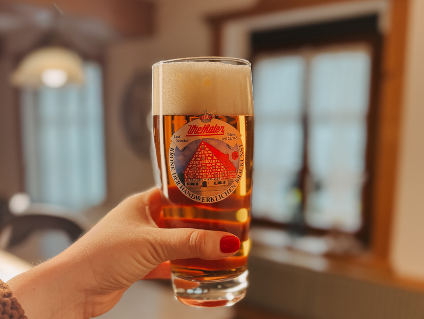Hand hält Bierglas mit Logo