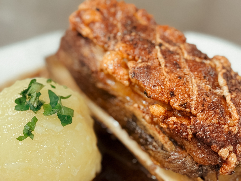 Schweinebraten mit links daneben Kartoffelknödel