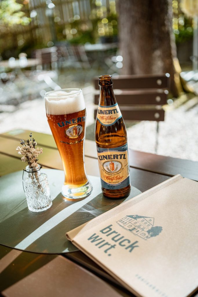Bierflasche und Weißbierglaß auf Biergartentisch